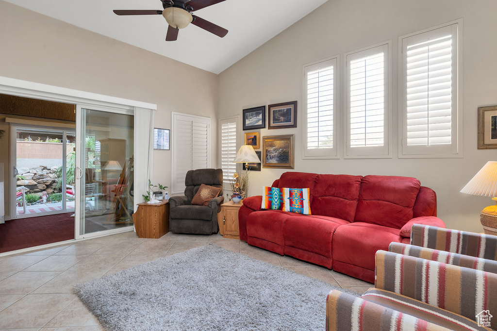 Living area with tile patterned flooring, high vaulted ceiling, a ceiling fan, and plenty of natural light