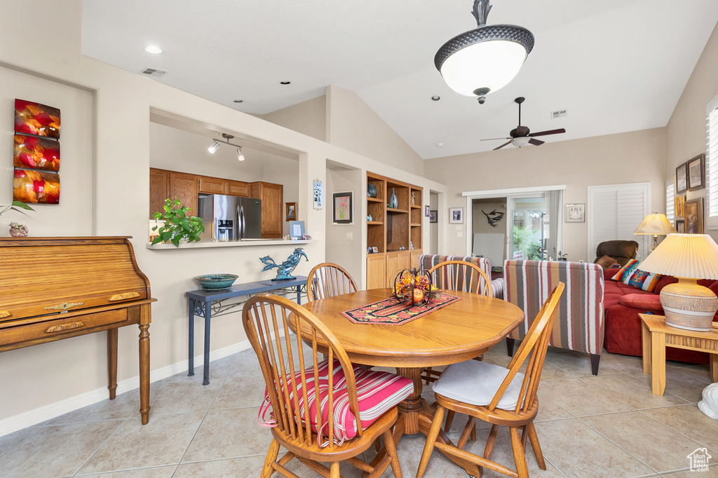 Dining space featuring vaulted ceiling, ceiling fan, light tile patterned flooring, and baseboards