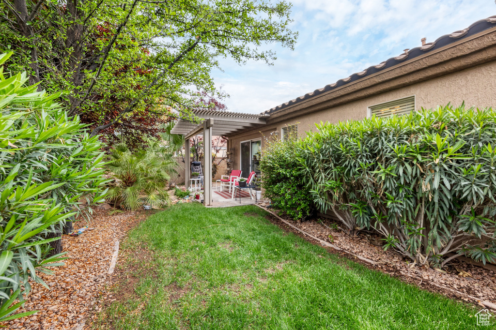 View of grassy yard featuring a pergola and a patio