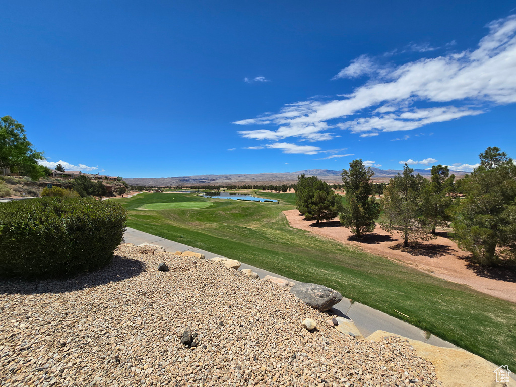 View of community with golf course view, a water and mountain view, and a yard