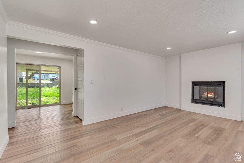 Unfurnished living room with crown molding, baseboards, a lit fireplace, and recessed lighting