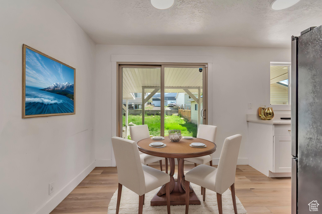 Dining area with a textured ceiling, baseboards, and light wood finished floors