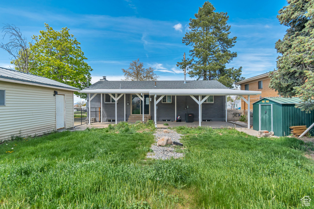 Back of house with a yard, an outbuilding, a shed, and a patio area