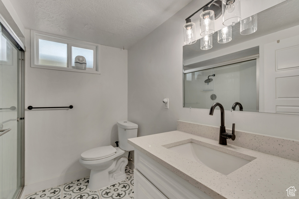 Bathroom with vanity, tile patterned flooring, toilet, a textured ceiling, and a stall shower