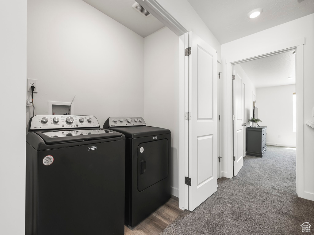 Laundry area featuring separate washer and dryer, carpet floors, and baseboards