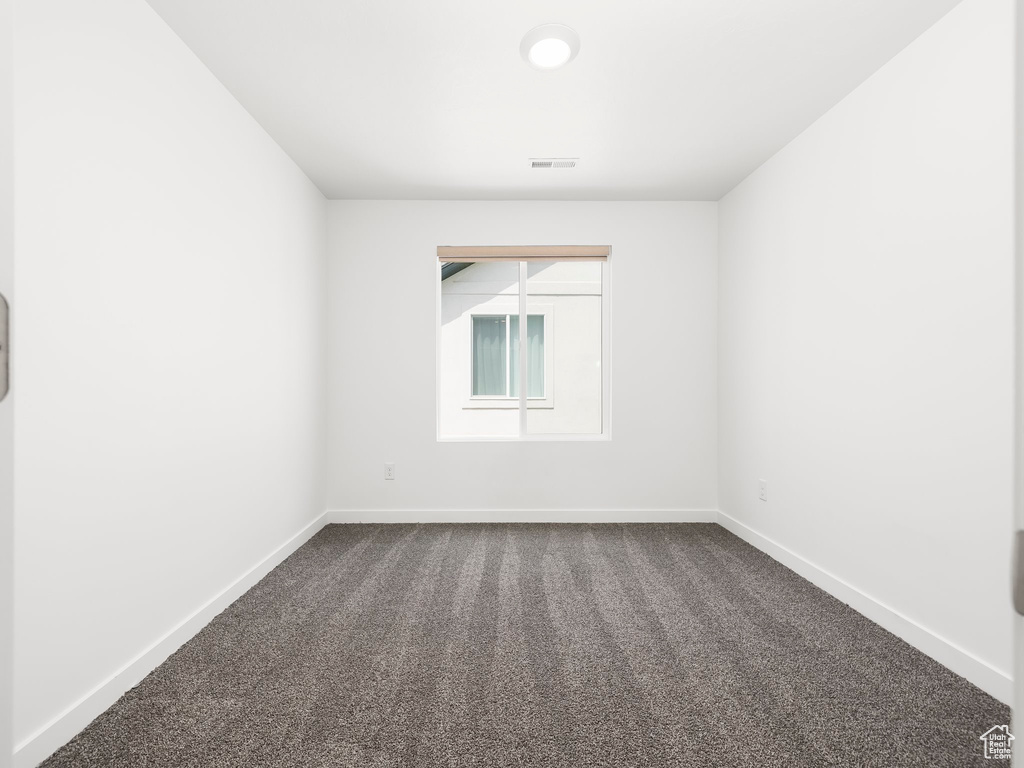 Empty room with dark colored carpet and baseboards