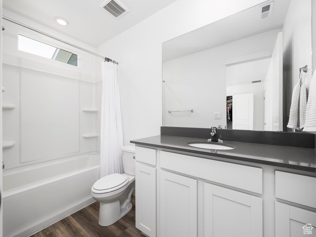 Bathroom with toilet, wood finished floors, vanity, and shower / tub combo with curtain