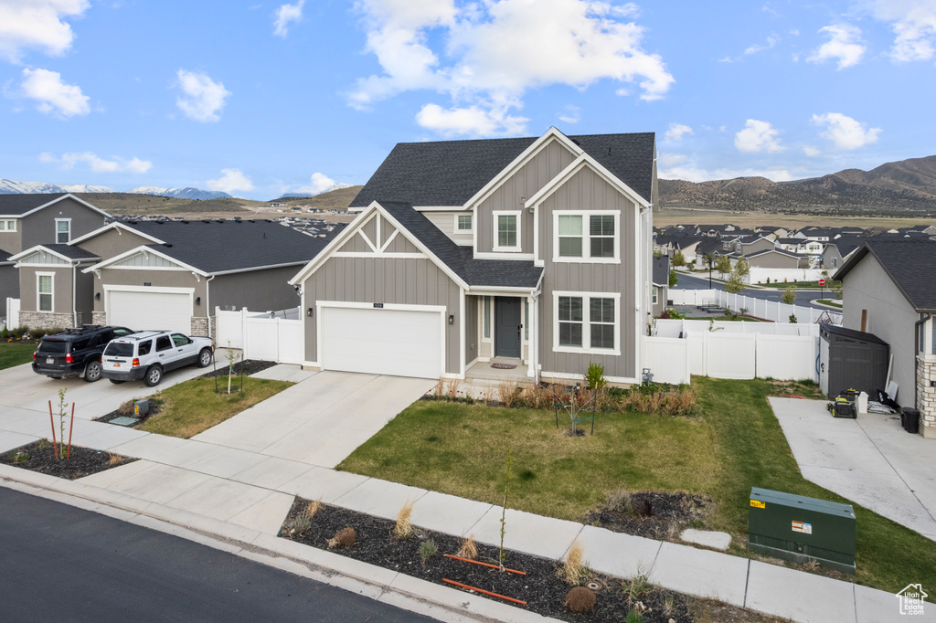 View of front of home with board and batten siding, concrete driveway, roof with shingles, a residential view, and a mountain view