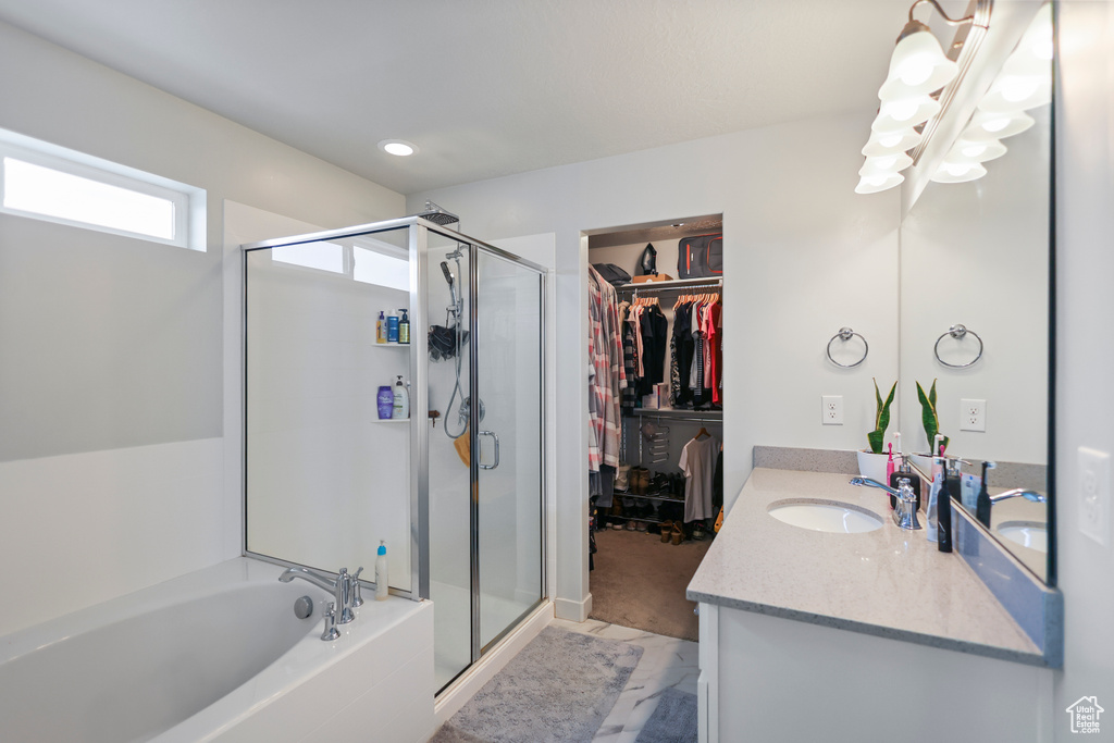 Full bath with a shower stall, vanity, a garden tub, a walk in closet, and recessed lighting