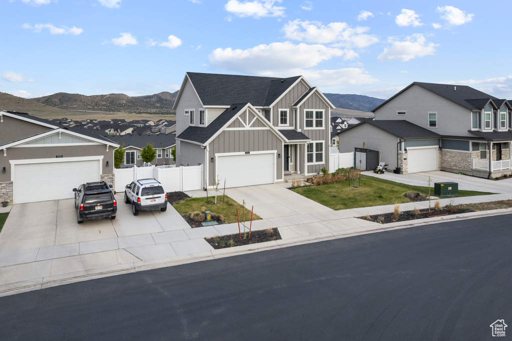 View of front facade featuring board and batten siding, a residential view, fence, a mountain view, and driveway