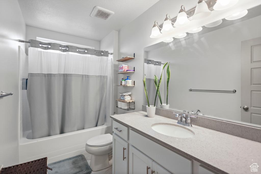 Full bathroom with shower / tub combo with curtain, toilet, and vanity