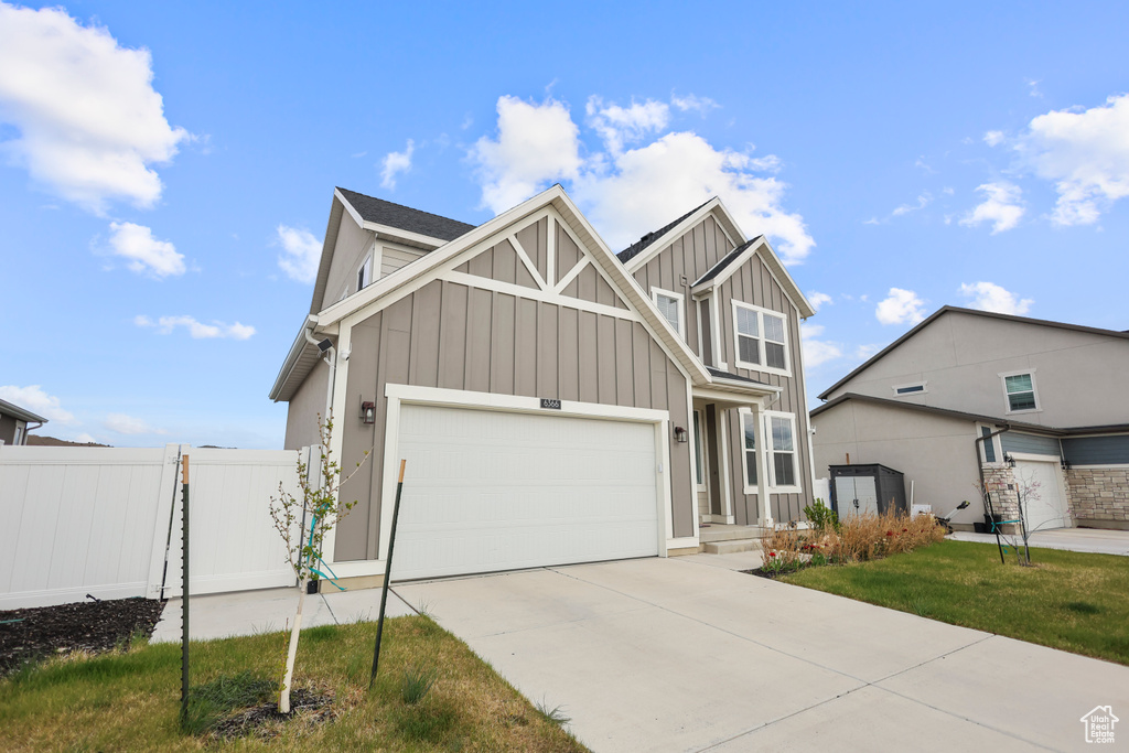 Craftsman inspired home featuring board and batten siding, fence, concrete driveway, and an attached garage