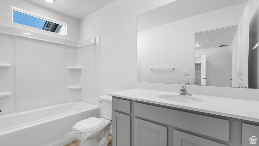 Bathroom with vanity, toilet, wood finished floors, and shower / bath combination