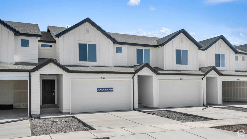 Multi unit property with board and batten siding, a garage, a shingled roof, and driveway