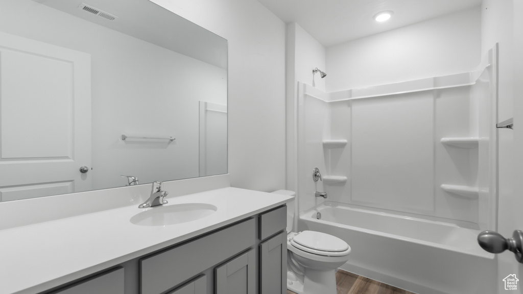 Full bathroom with wood finished floors, toilet, vanity, and shower / tub combination