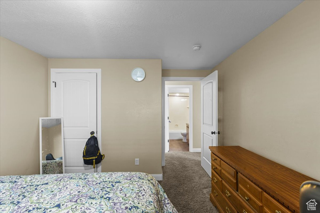 Bedroom featuring dark carpet, baseboards, and a textured ceiling