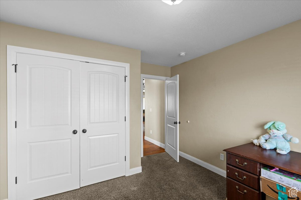Bedroom with baseboards, a closet, and dark colored carpet