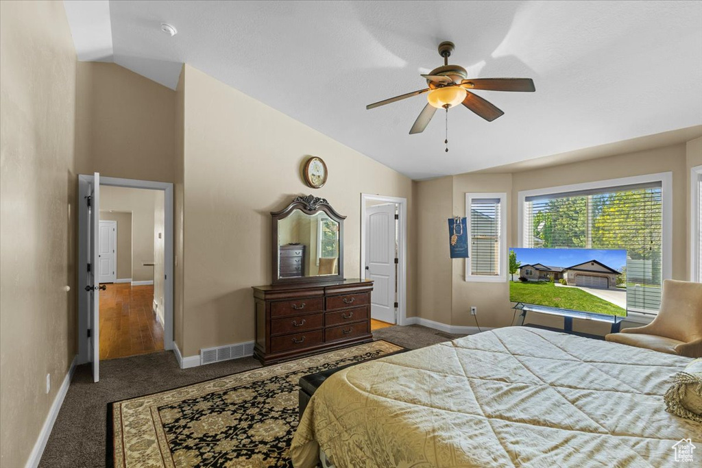 Carpeted bedroom with a ceiling fan, visible vents, baseboards, and lofted ceiling