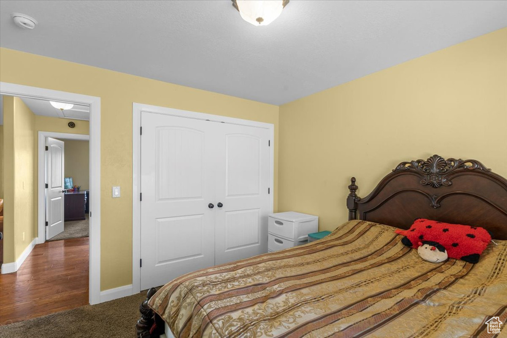 Carpeted bedroom with baseboards, a closet, and wood finished floors