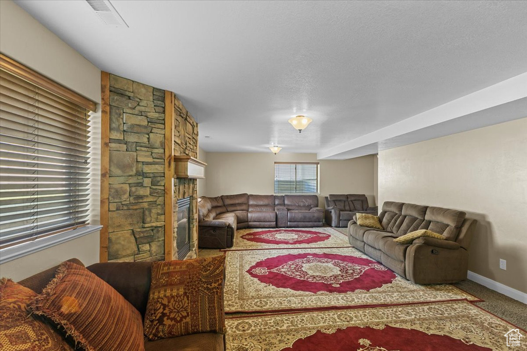 Living room with carpet flooring, visible vents, baseboards, and a fireplace