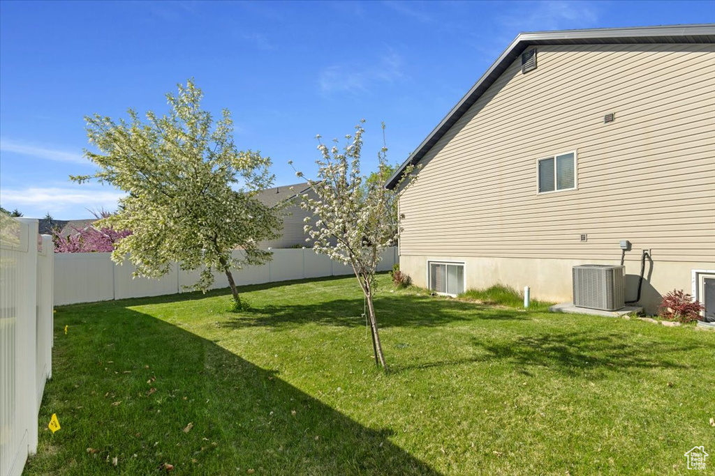 View of property exterior with a lawn, cooling unit, and a fenced backyard