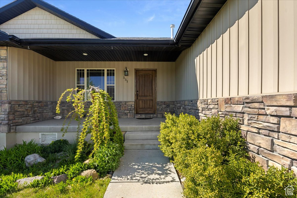 Property entrance featuring stone siding and board and batten siding