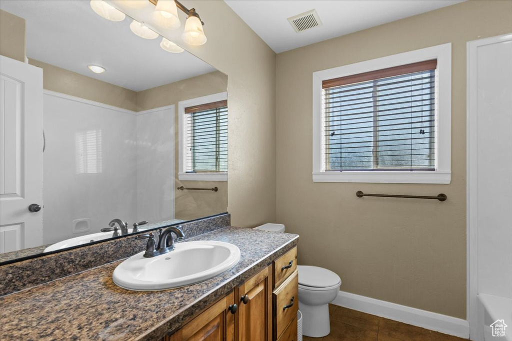 Bathroom featuring toilet, vanity, visible vents, a bathing tub, and baseboards