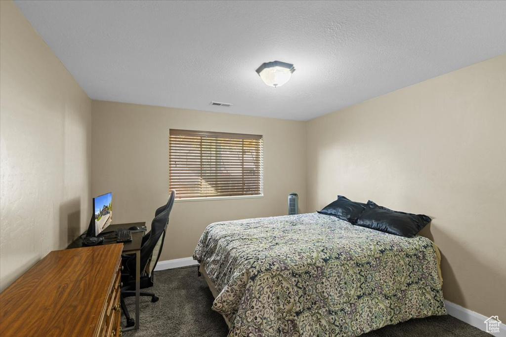 Carpeted bedroom featuring baseboards and a desk