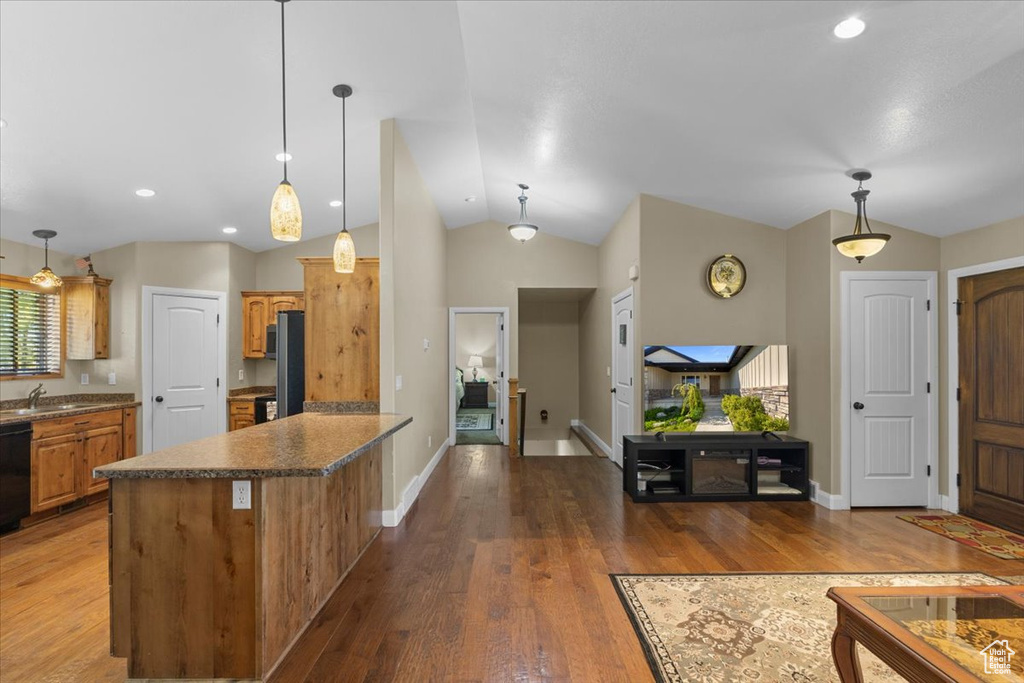 Kitchen with decorative light fixtures, baseboards, a sink, a peninsula, and wood finished floors