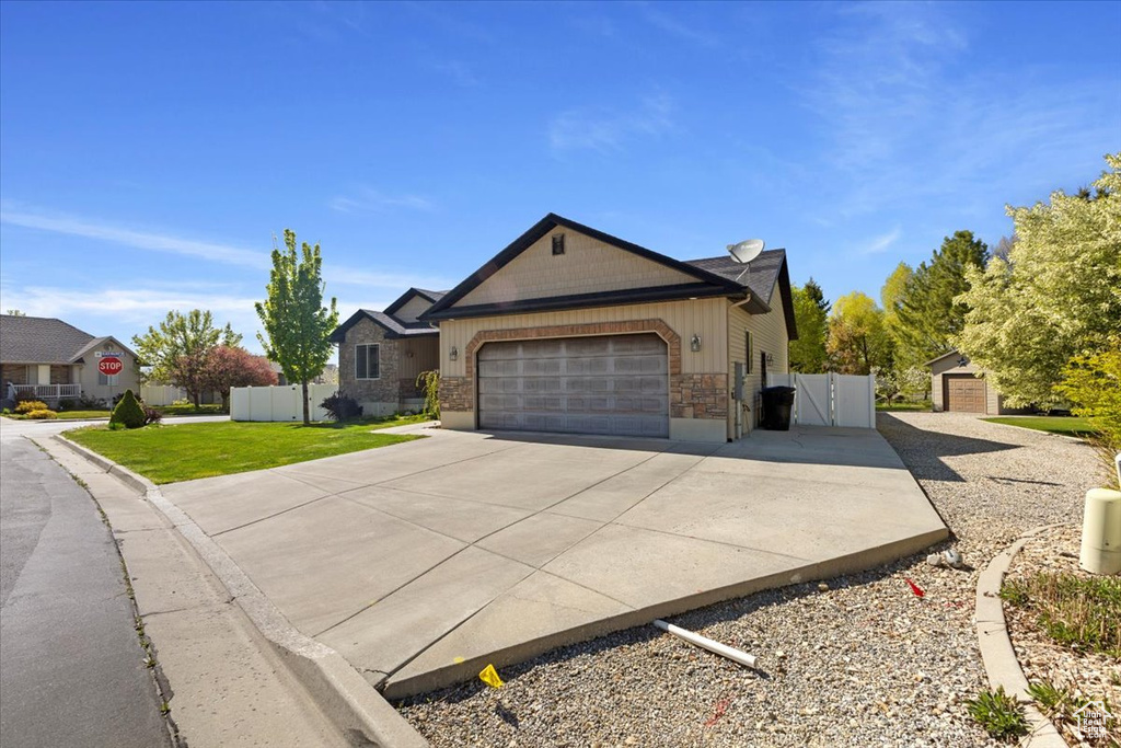 Ranch-style home featuring driveway, fence, a garage, stone siding, and a gate