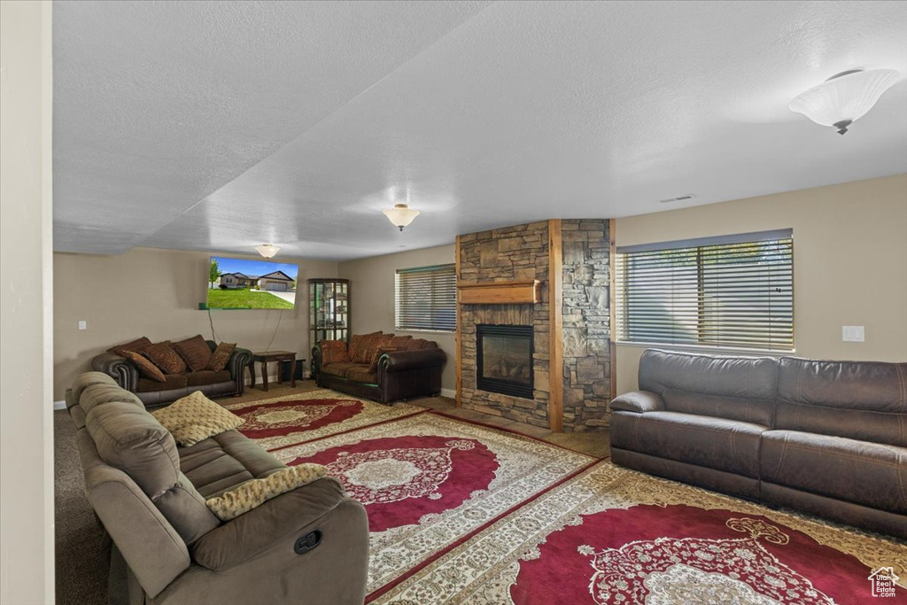 Living room with a fireplace, a textured ceiling, and carpet