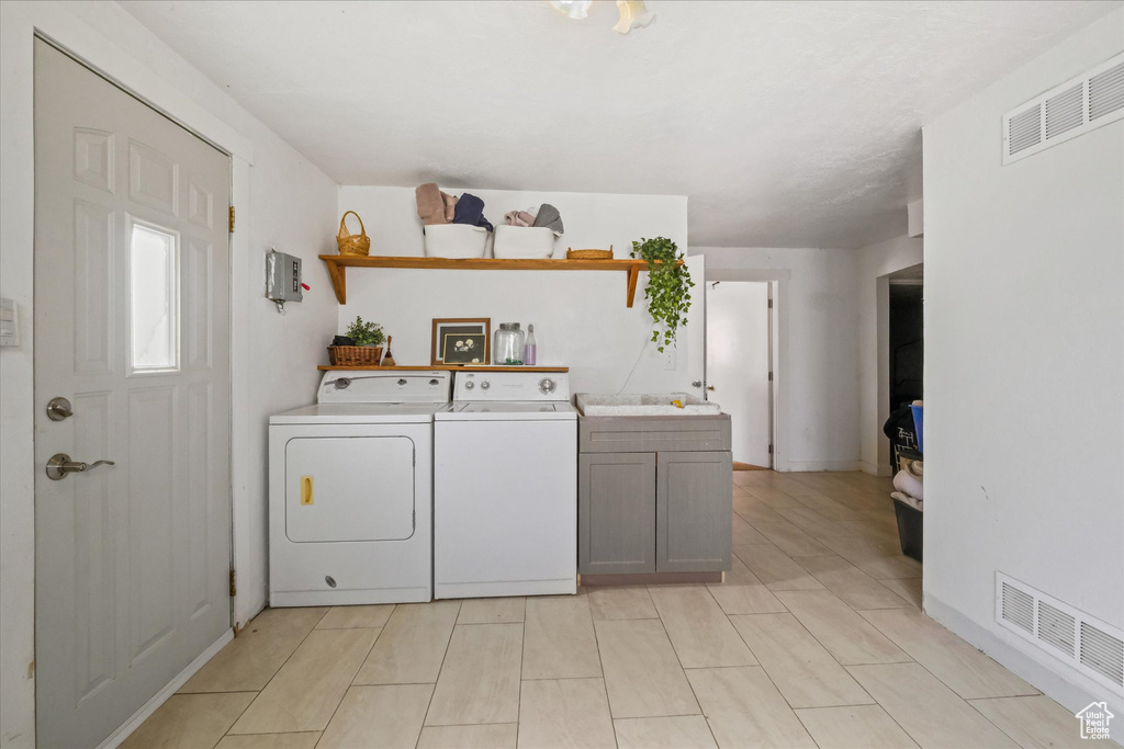 Clothes washing area featuring washing machine and clothes dryer and cabinet space