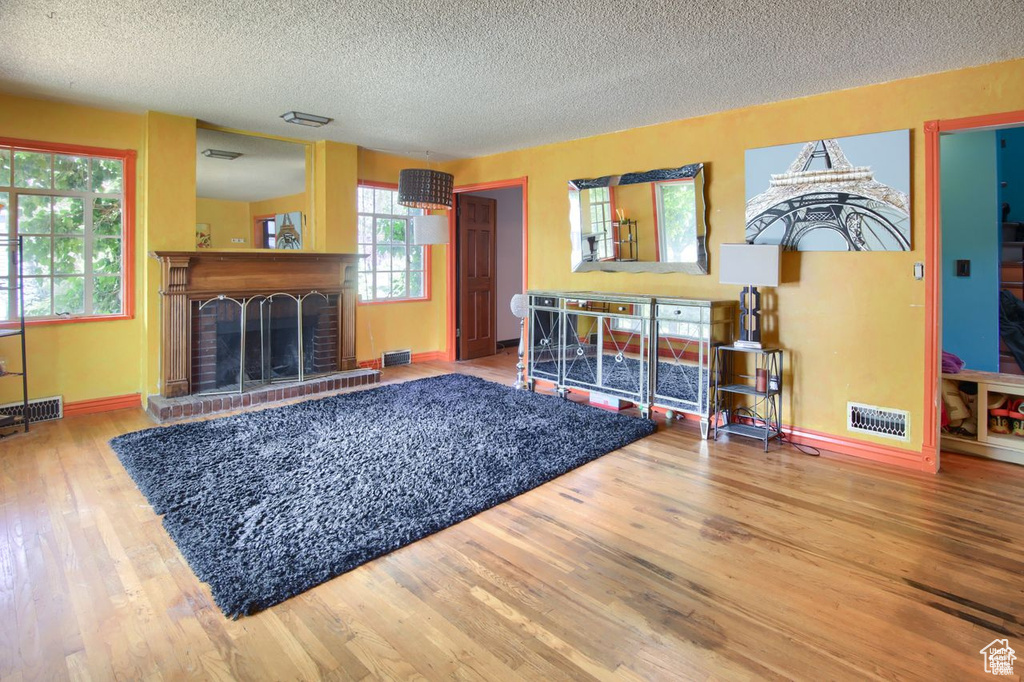 Living area featuring a textured ceiling, wood finished floors, a fireplace, and baseboards