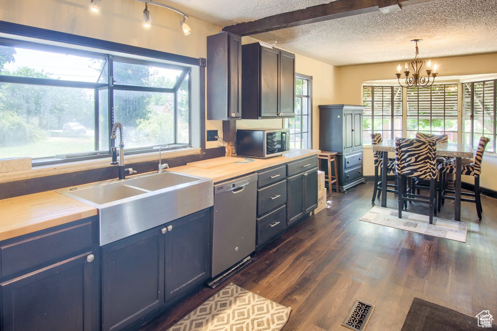 Kitchen with stainless steel appliances, a textured ceiling, a sink, a chandelier, and dark wood-style flooring