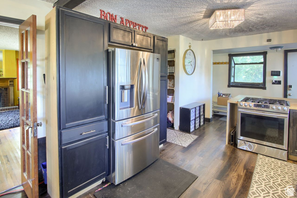 Kitchen with stainless steel appliances, a textured ceiling, and dark wood-type flooring