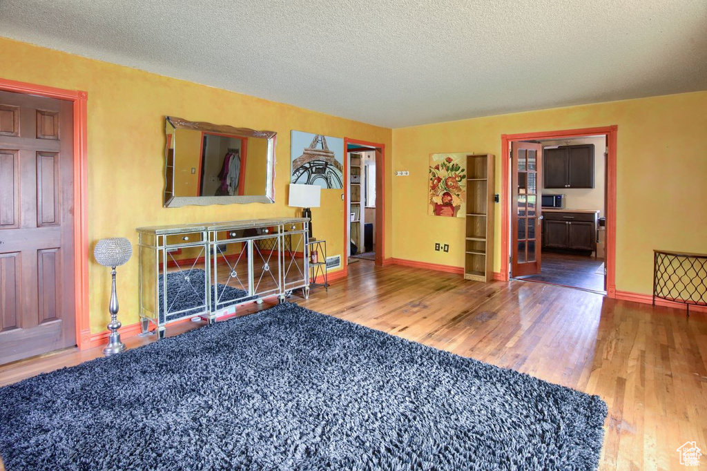Living area with wood finished floors, a textured ceiling, and baseboards