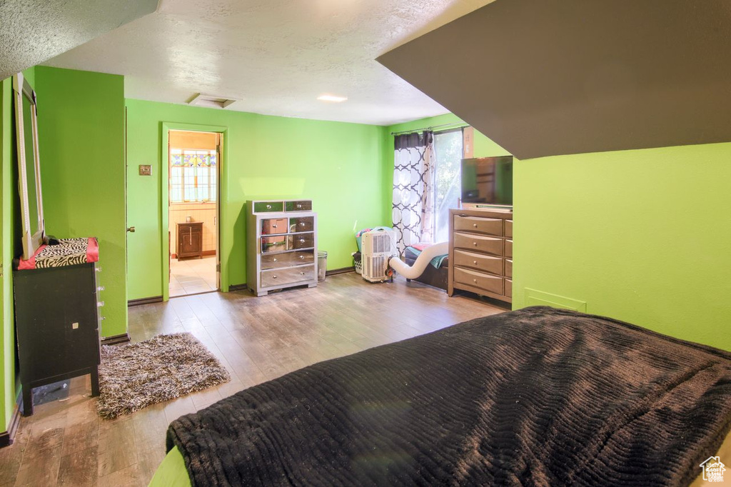 Bedroom with wood finished floors, multiple windows, and a textured ceiling