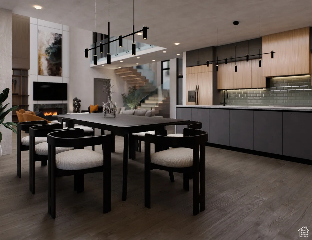 Dining area with a lit fireplace, dark wood-type flooring, stairway, recessed lighting, and a high ceiling