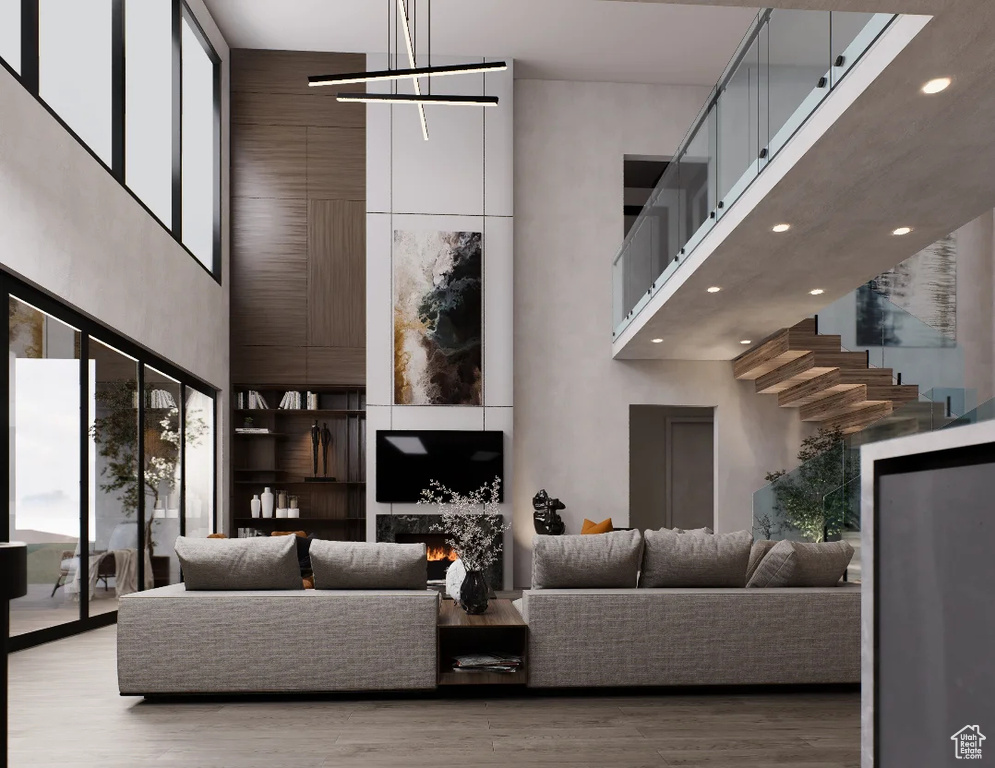 Living area featuring a high ceiling, recessed lighting, wood finished floors, and a chandelier