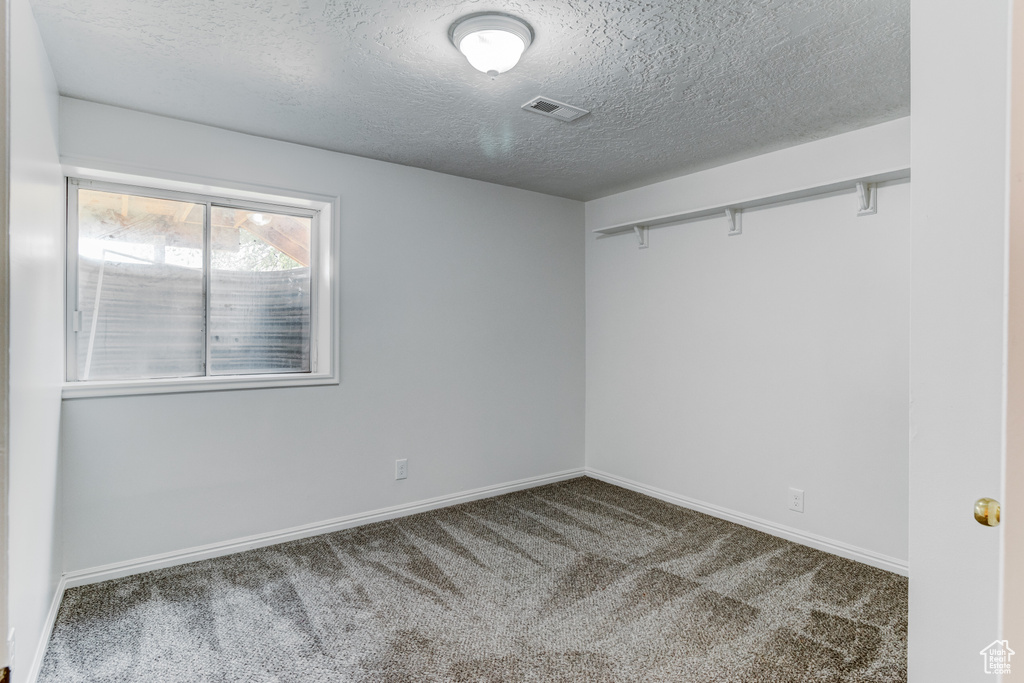 Spare room with carpet, a textured ceiling, and baseboards