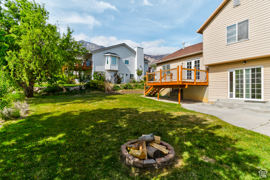 View of grassy yard featuring an outdoor fire pit, stairway, a deck, a patio area, and a residential view