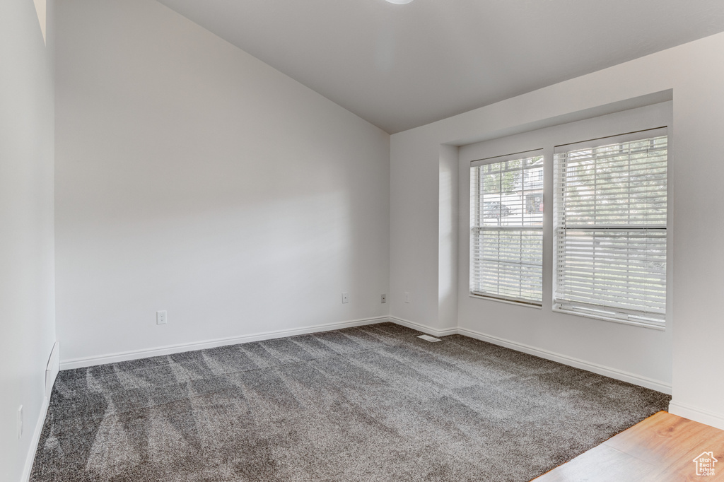 Carpeted spare room with lofted ceiling and baseboards