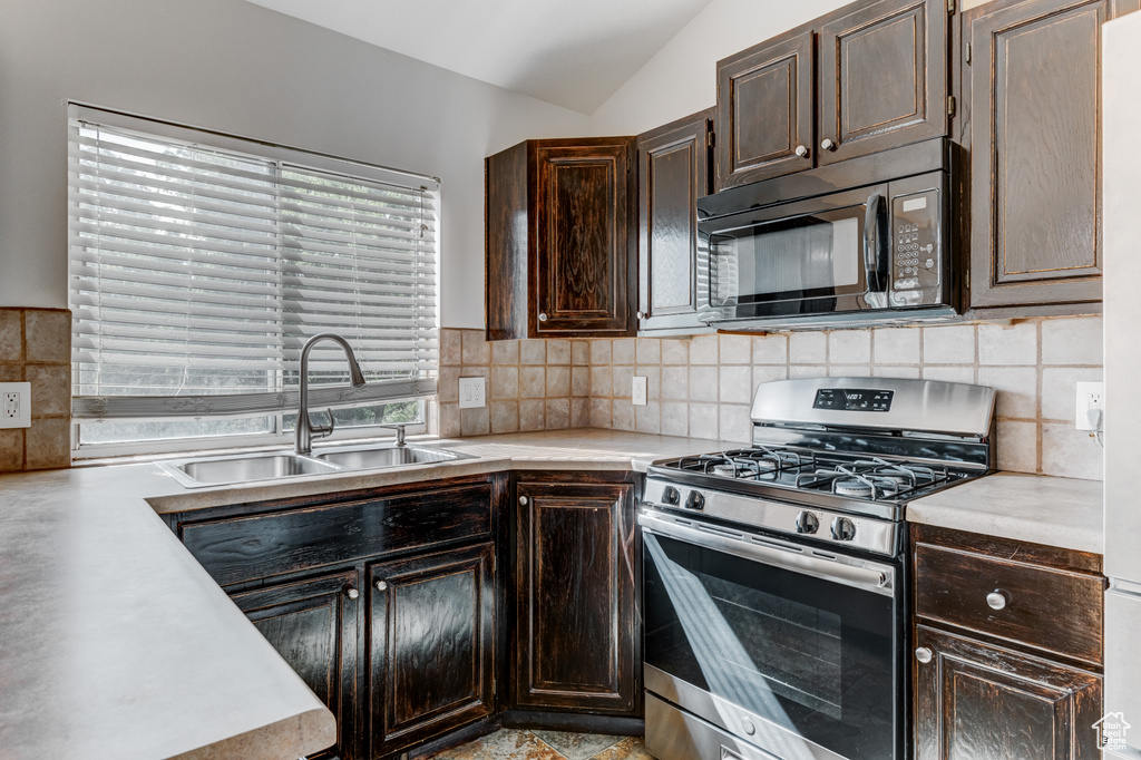 Kitchen featuring black microwave, stainless steel gas range, a sink, light countertops, and dark brown cabinetry