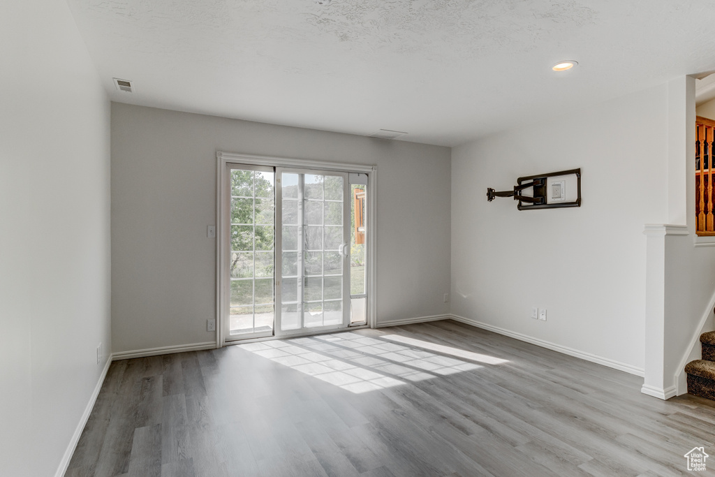 Unfurnished room featuring wood finished floors, stairway, baseboards, and recessed lighting