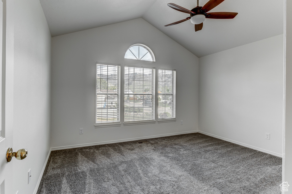 Spare room featuring a ceiling fan, carpet flooring, vaulted ceiling, and baseboards