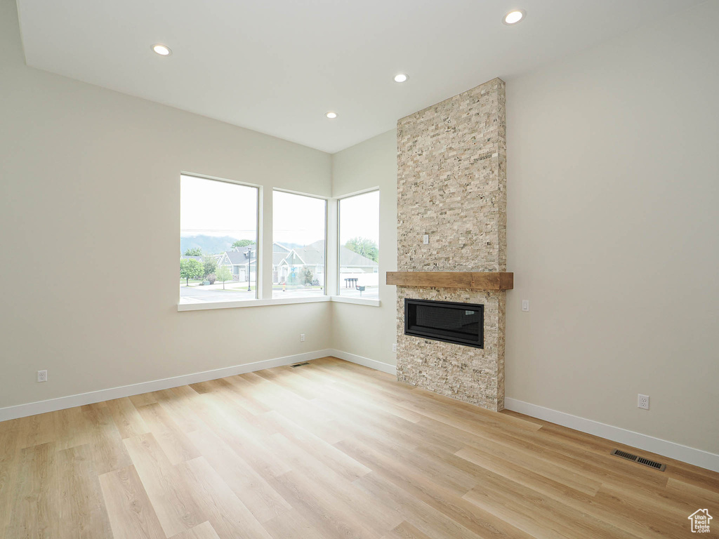 Unfurnished living room with recessed lighting, light wood finished floors, a fireplace, and baseboards