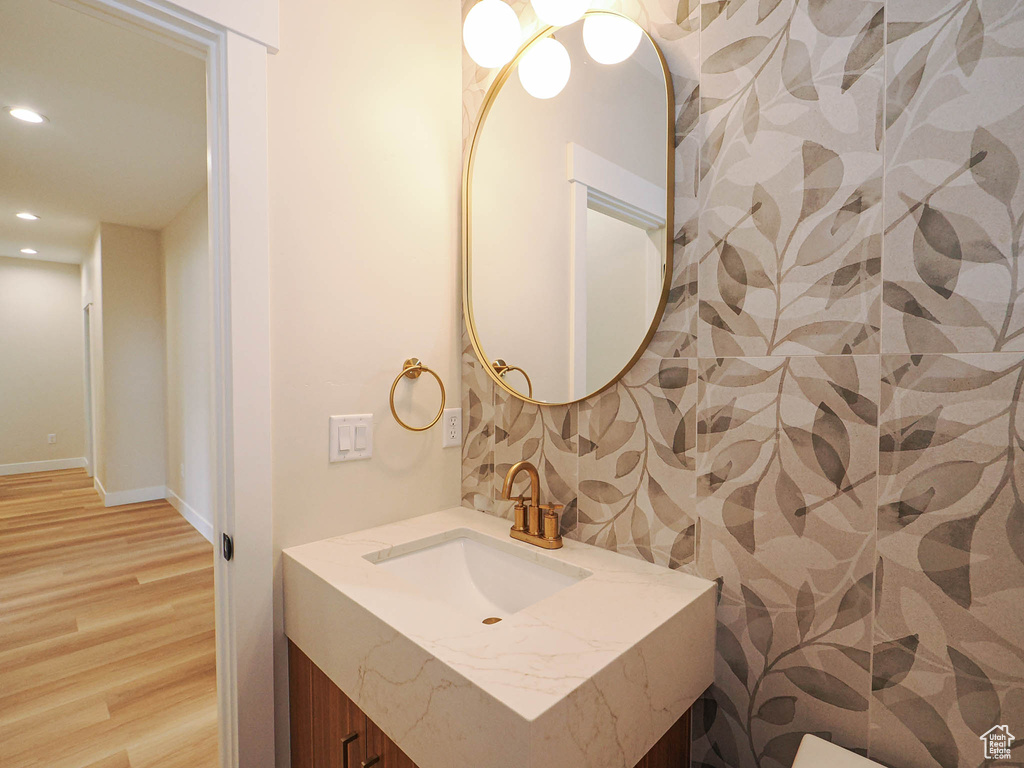 Bathroom with recessed lighting, wood finished floors, vanity, and baseboards