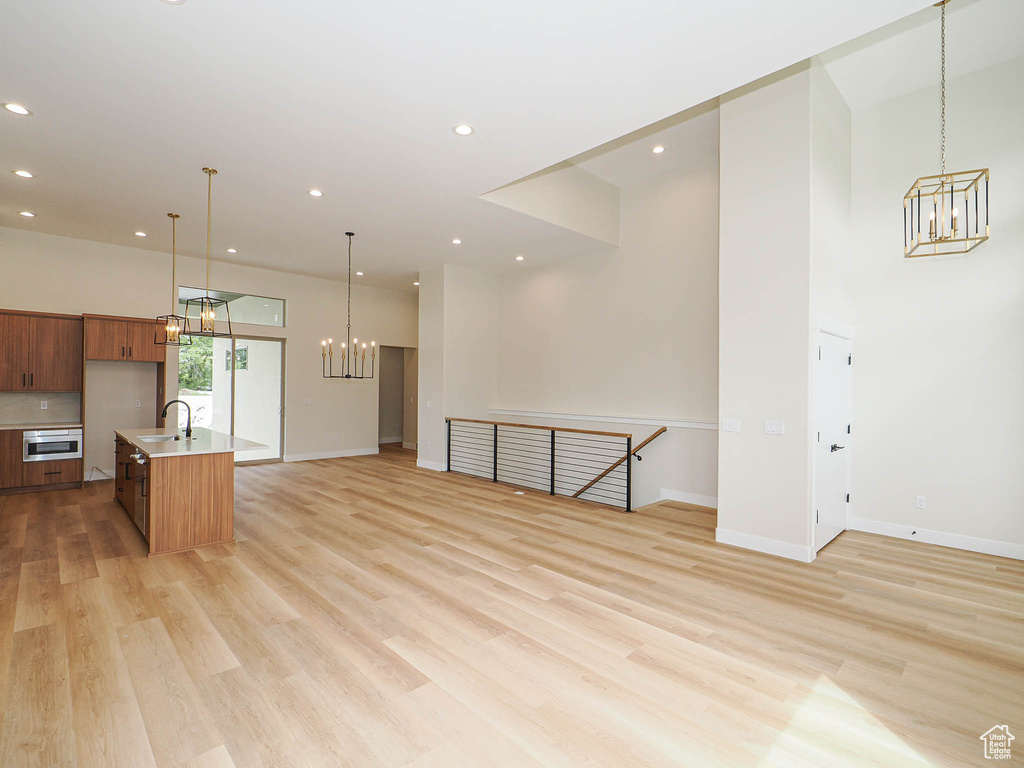 Kitchen with a chandelier, open floor plan, light countertops, a sink, and recessed lighting