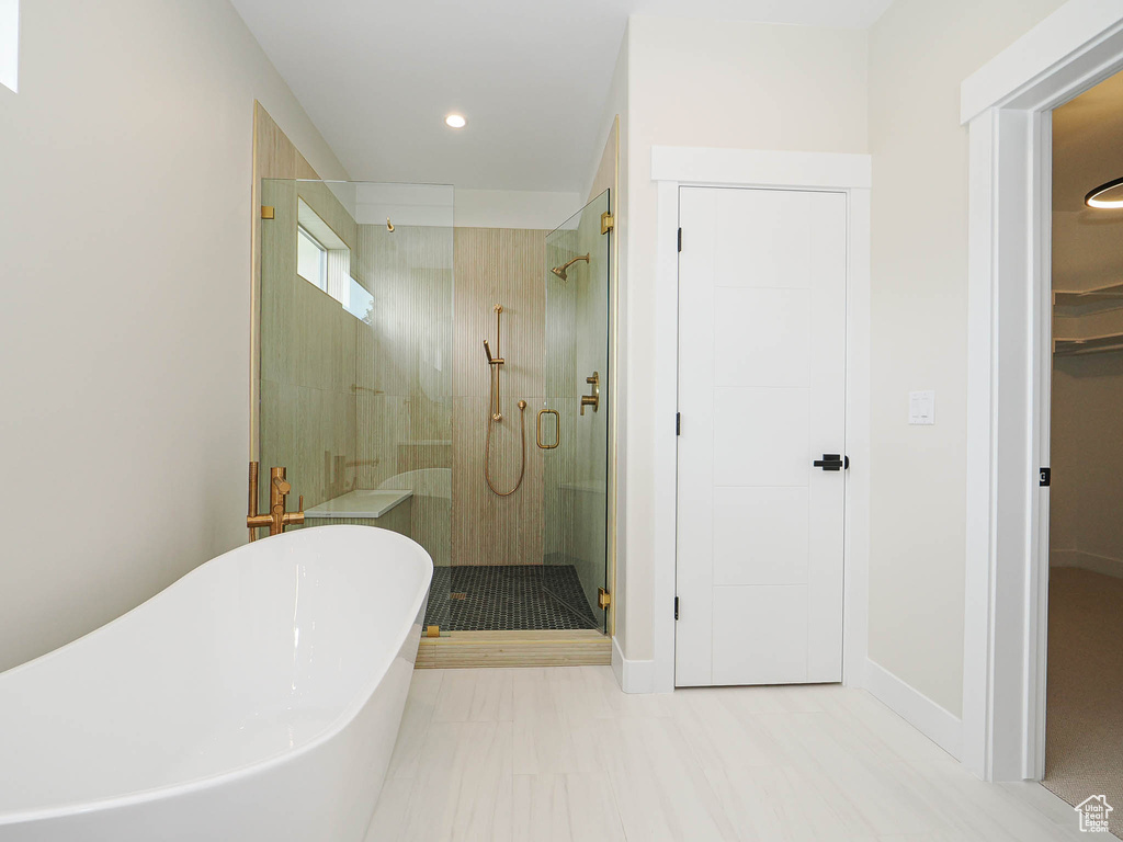 Full bath featuring a shower stall, a freestanding tub, and recessed lighting