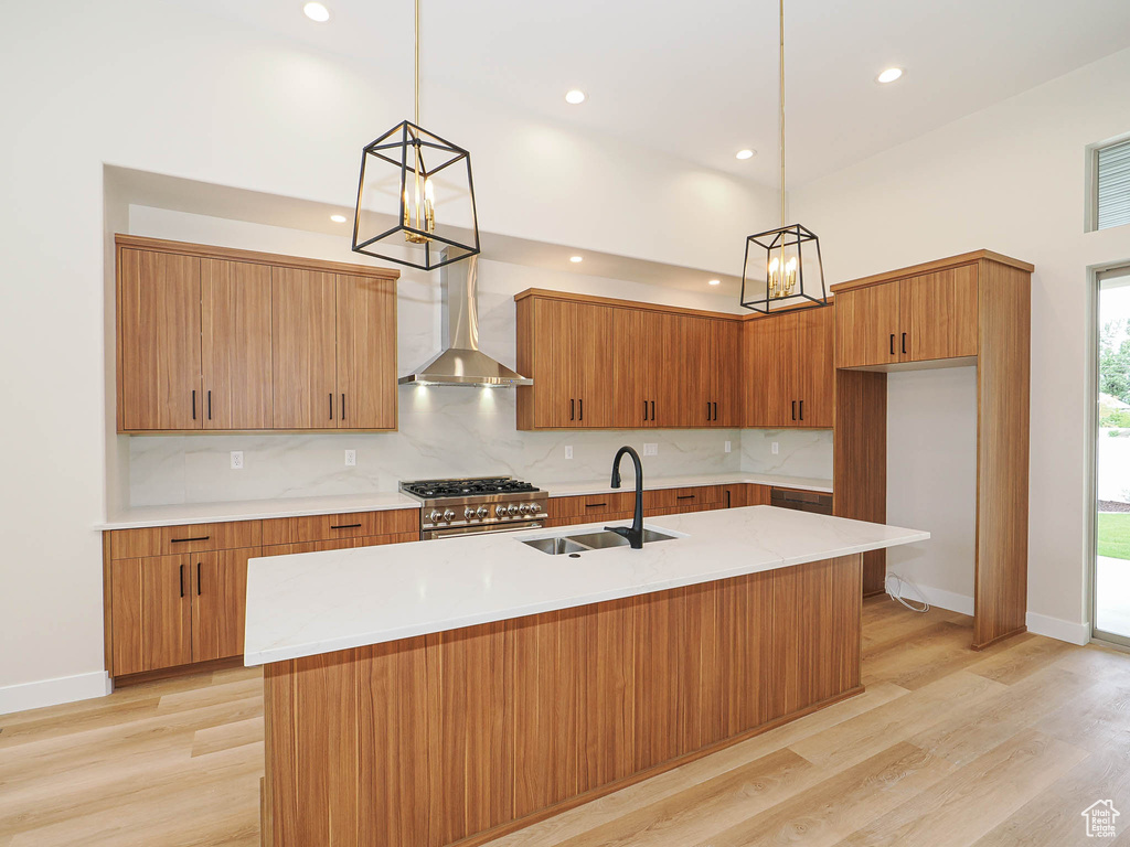 Kitchen featuring wall chimney exhaust hood, a sink, tasteful backsplash, light countertops, and recessed lighting